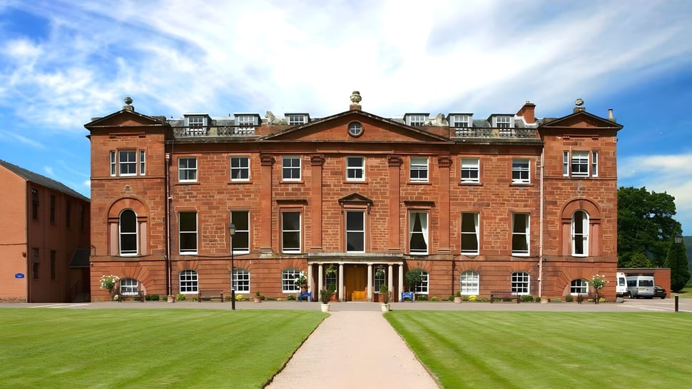 El edificio principal de ladrillo rojo de la Kilgraston School se encuentra frente a un césped bien cuidado bajo un cielo azul.