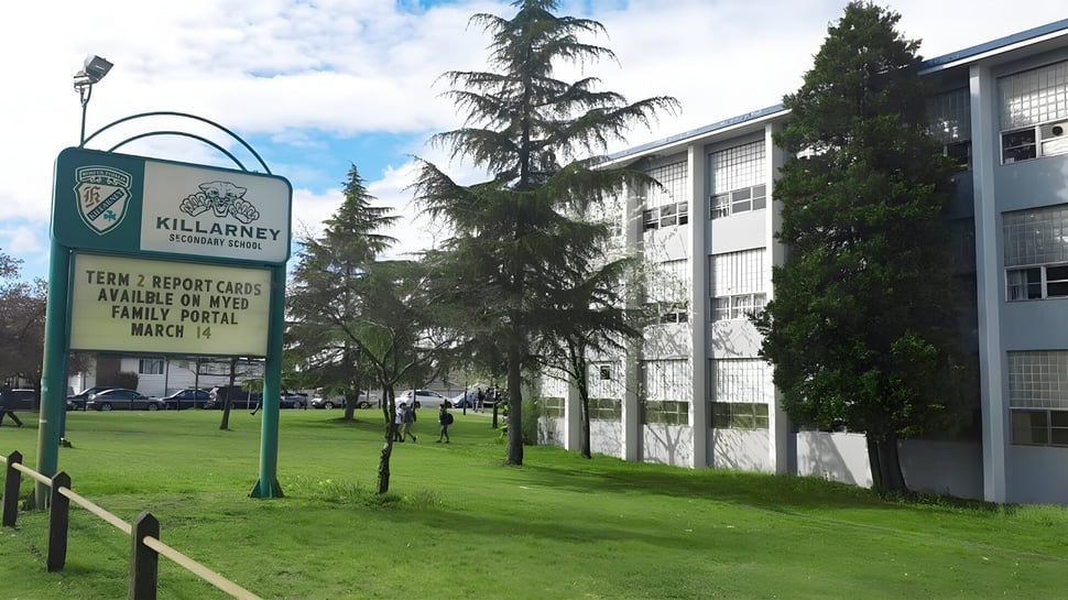 El edificio de la Killarney Secondary School se ve detrás de un cartel verde del Community Center.
