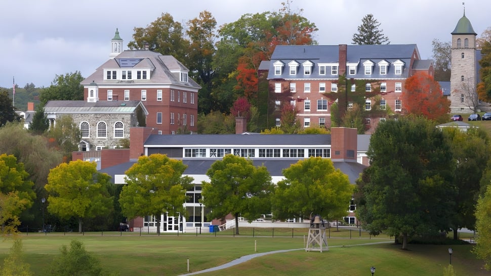 El campus de la Kimball Union Academy muestra edificios históricos y modernos rodeados de colorido follaje de otoño bajo un cielo nublado.
