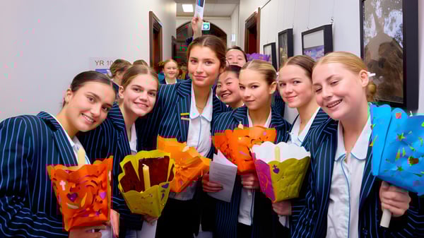 Estudiantes de Kincoppal-Rose Bay están en el pasillo con ramos de flores coloridas en la mano.