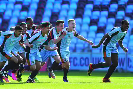Un grupo de jugadores de fútbol de la King Edward's Witley School celebra en el campo.