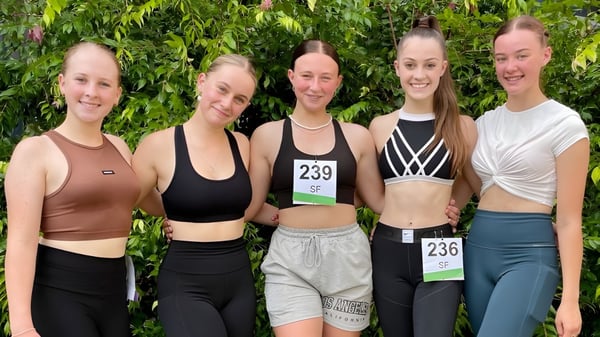 Un grupo de cinco alumnas en ropa deportiva está en el área exterior verde de la Kingaroy State High School.