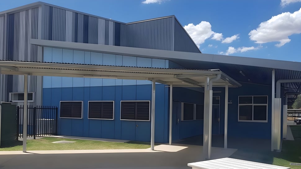 El moderno edificio de la Kingaroy State High School muestra una fachada azul con entrada cubierta y una zona de césped delante.