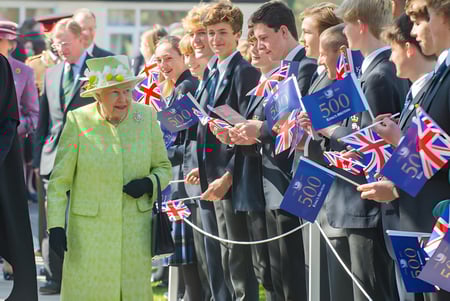 Estudiantes de King's Bruton reciben a una mujer con un abrigo verde con banderas y pancartas británicas.