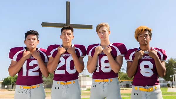 Cuatro estudiantes de la Kings Christian School están frente a una gran cruz al aire libre.