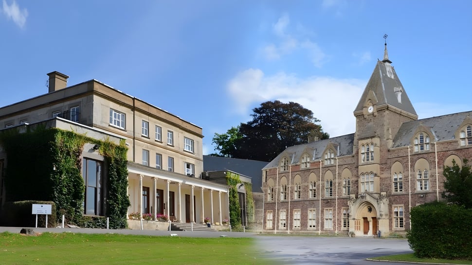 El edificio histórico con alta torre en el campus del King's College está rodeado de exuberante vegetación y un patio pavimentado.