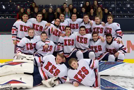 Un grupo de jugadoras y jugadores de hockey de la King’s-Edgehill School posan juntos en la pista de hielo con sus uniformes de equipo.