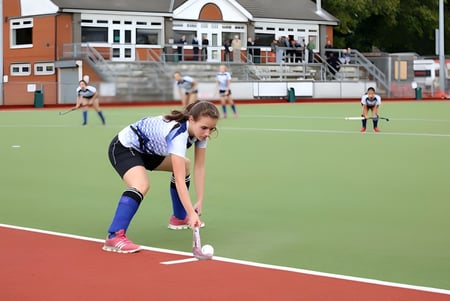 Un estudiante de la King's School Rochester está en ropa deportiva en el campo deportivo en una posición de cuclillas.