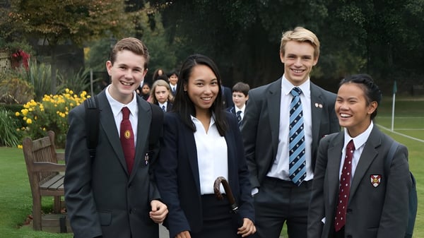 Un grupo de estudiantes en ropa formal está de pie juntos en un jardín en el terreno de la King's School Rochester.