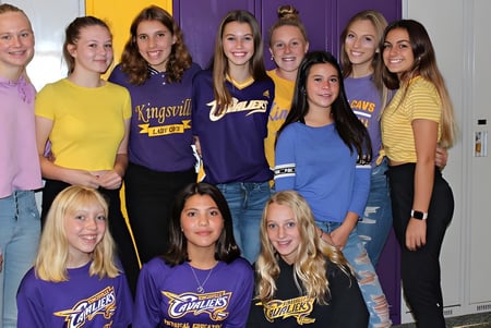 Un grupo de estudiantes posa frente a un fondo colorido en el campus de la Kingsville District High School.