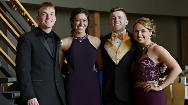 Cuatro personas vestidas formalmente están juntas en una sala decorativa en el campus de la Kingsville District High School.
