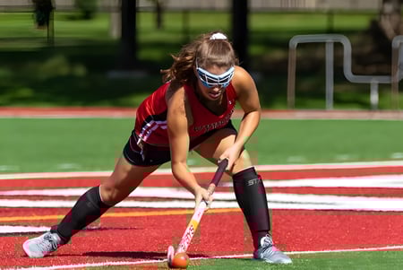 Una estudiante de Kingswood Oxford está en ropa deportiva con un stick de hockey en la pista en espera.