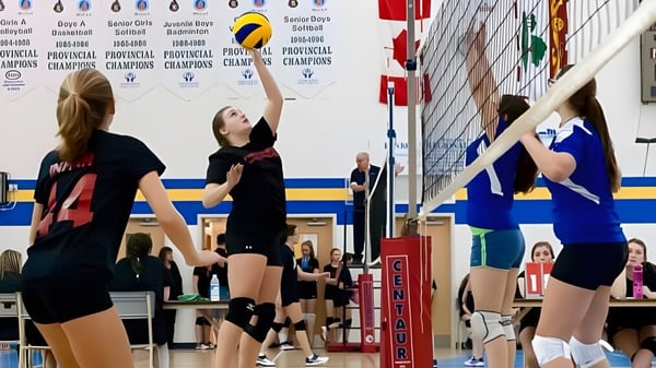 Alumnos y alumnas de la Kinkora Regional High School juegan al voleibol en el gimnasio.