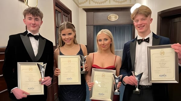 Cuatro personas de la Kirkham Grammar School sostienen premios en una sala con una decoración espléndida.