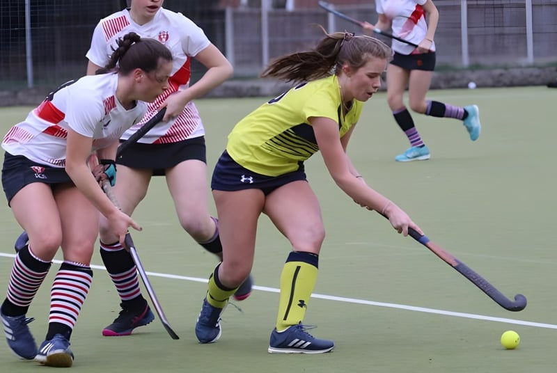 Un grupo de jóvenes mujeres juega al hockey sobre césped en el campo de deportes de la Kirkham Grammar School.