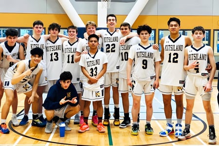 Un grupo de estudiantes de la Kitsilano Secondary School posan juntos en la cancha de baloncesto con una canasta visible al fondo.