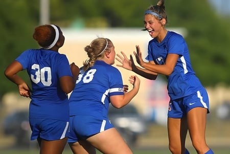 Un grupo de jóvenes futbolistas celebra juntos en el campo de la Kokomo High School.
