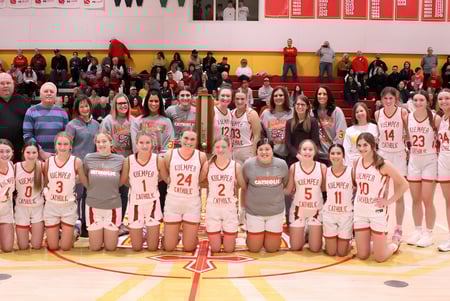 Un grupo de estudiantes de la Kuemper Catholic High School posan en la cancha de baloncesto para una foto de equipo.
