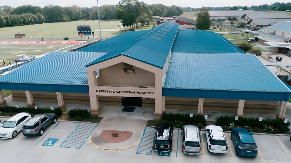 El edificio principal de Lafayette Christian Academy con techo de metal azul y estacionamiento en un entorno rural.