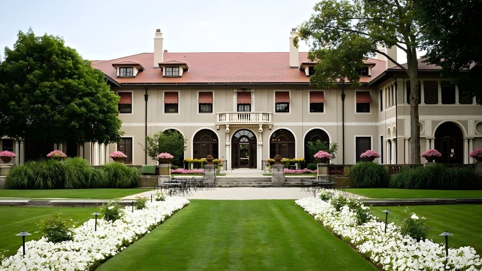 El histórico edificio de la Lake Forest Academy está rodeado de praderas verdes y un camino con flores blancas.