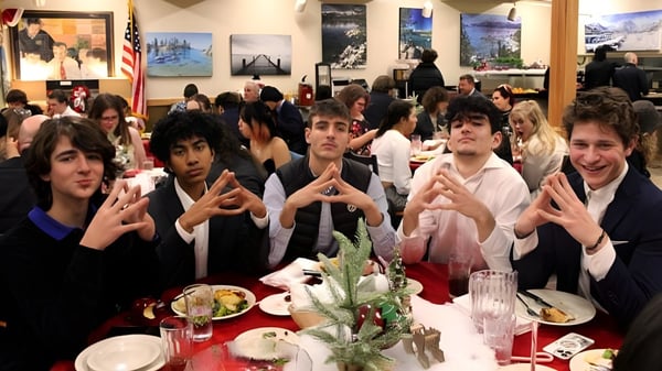 Estudiantes de la Lake Tahoe Preparatory School están sentados en un comedor concurrido con obras de arte visibles en las paredes.