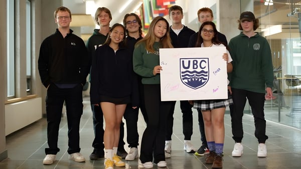 Un grupo de estudiantes de la Lakefield College School está en el pasillo sosteniendo un cartel con el logo de UBC.