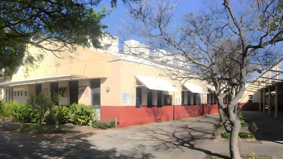 El colorido edificio bicolor de la Lakeland Senior High School está rodeado de árboles y se encuentra junto a un camino pavimentado.