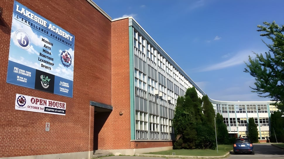 El edificio de ladrillo de Lakeside Academy está rodeado de árboles bajo un cielo azul claro.