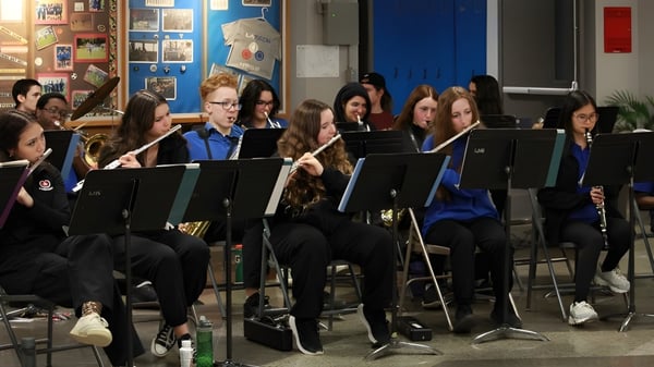 Estudiantes de Lakeside Academy tocan juntos instrumentos musicales en el aula con coloridas obras de arte en las paredes.