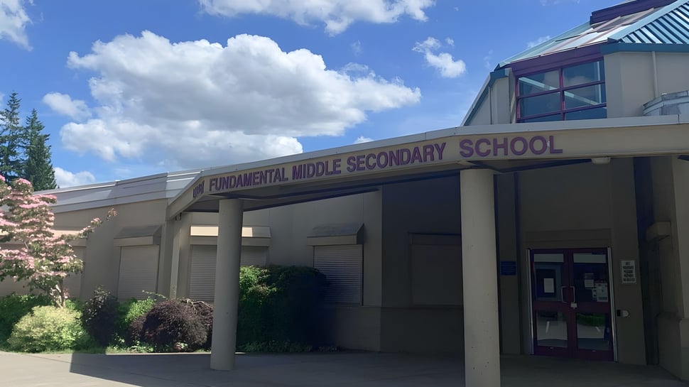 El moderno edificio escolar de la Langley Fundamental Middle and Secondary School se encuentra bajo un cielo azul con nubes blancas.