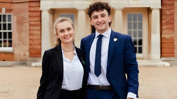 Una joven pareja está frente a un edificio de ladrillo en el campus de la Langley School.