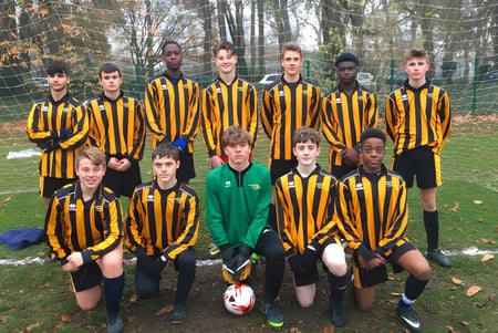 Un grupo de jóvenes futbolistas está en el campo de deportes de la Larkmead School con camisetas amarillas y negras.