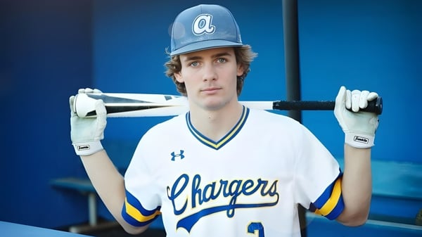 Un alumno del Las Virgenes Unified School District está con un bate de béisbol frente a un fondo azul.