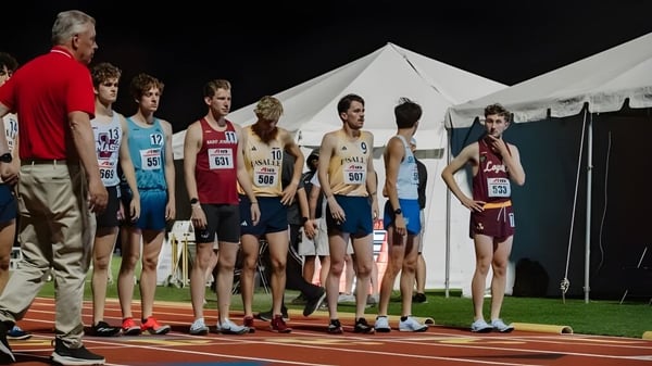 Un grupo de atletas masculinos del LaSalle College Vancouver está en la pista frente a carpas bajo un cielo nublado.