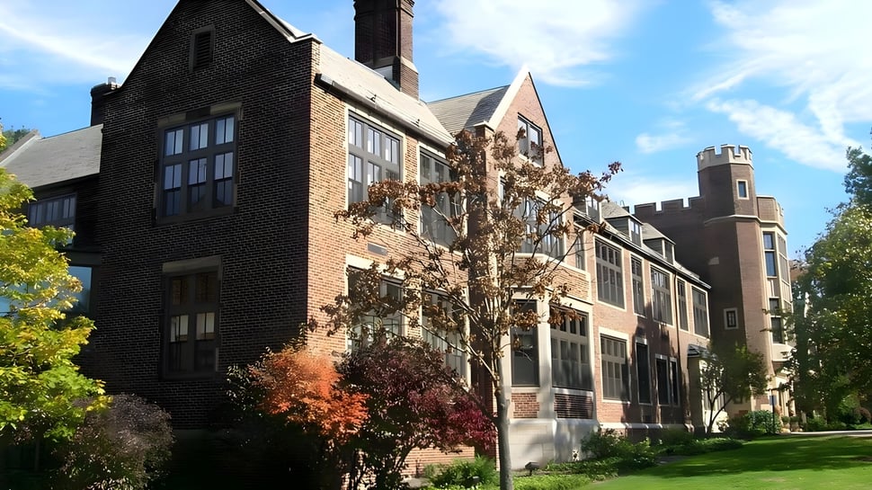 El impresionante edificio de ladrillo de la Laurel School está rodeado de plantas y árboles verdes.