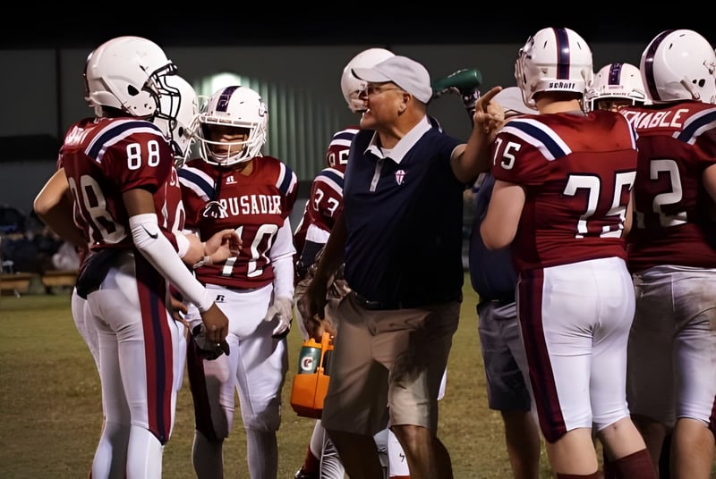 Estudiantes y un entrenador de la Laurens Academy están en uniforme de fútbol en un campo de juego por la noche.