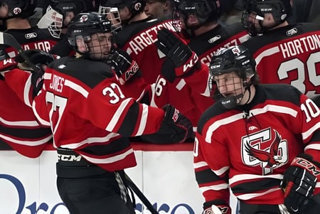 Un grupo de jugadores de hockey con camisetas rojas juega sobre el hielo en el terreno de Laurier MacDonald High School.