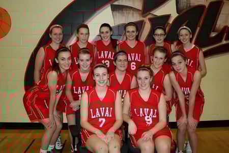 Un grupo de jóvenes estudiantes de Laval High School en uniformes rojos posando en el gimnasio frente a un gran mural de baloncesto.