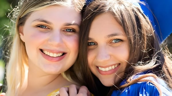 Dos estudiantes de la Lawrence Woodmere Academy se abrazan al aire libre frente a un fondo verde.