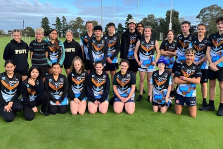 Un grupo de jóvenes atletas de la Le Fevre High School posan en un campo de césped frente a árboles y un cielo azul.