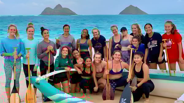 Un grupo de estudiantes de la Le Jardin Academy está junto en ropa deportiva en un barco frente a un fondo con islas y agua turquesa.