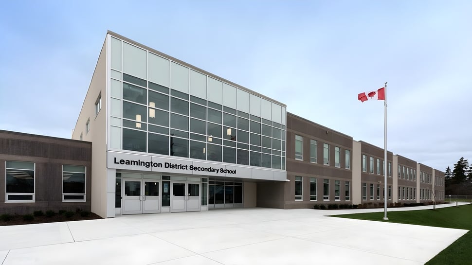El moderno edificio escolar de la Leamington District Secondary School con bandera canadiense y área exterior ajardinada.