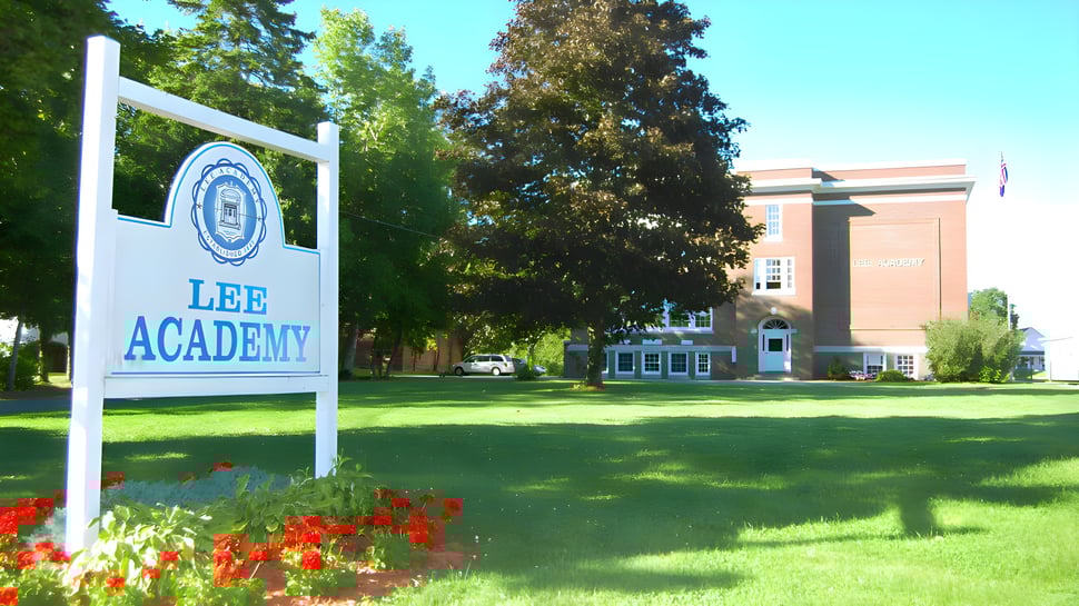 Un cartel con el nombre Lee Academy está frente a un edificio de ladrillo de varios pisos en el campus de Lee Academy.