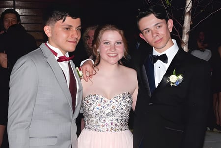 Tres personas en ropa formal posan juntas en un evento de Lee Academy.