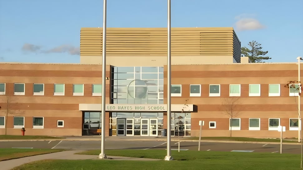 El edificio de la Leo Hayes High School muestra una fachada moderna de ladrillo y madera con grandes ventanas y una entrada.