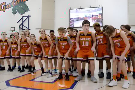 Un grupo de jóvenes jugadores y jugadoras de baloncesto de la Lethbridge School Division se reúne en un gimnasio.