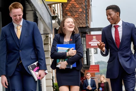 Tres personas vestidas profesionalmente caminan juntas por una calle en el terreno de la Lewes Old Grammar School.