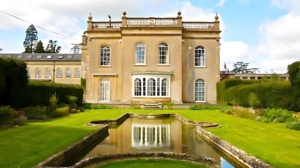 El edificio representativo de la Leweston School se encuentra en un jardín bien cuidado y se refleja en un estanque tranquilo.