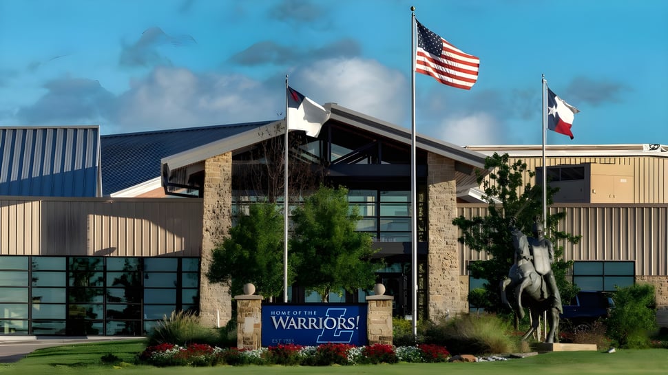 El moderno edificio de la Liberty Christian Academy con la bandera americana y texana frente a un entorno verde.