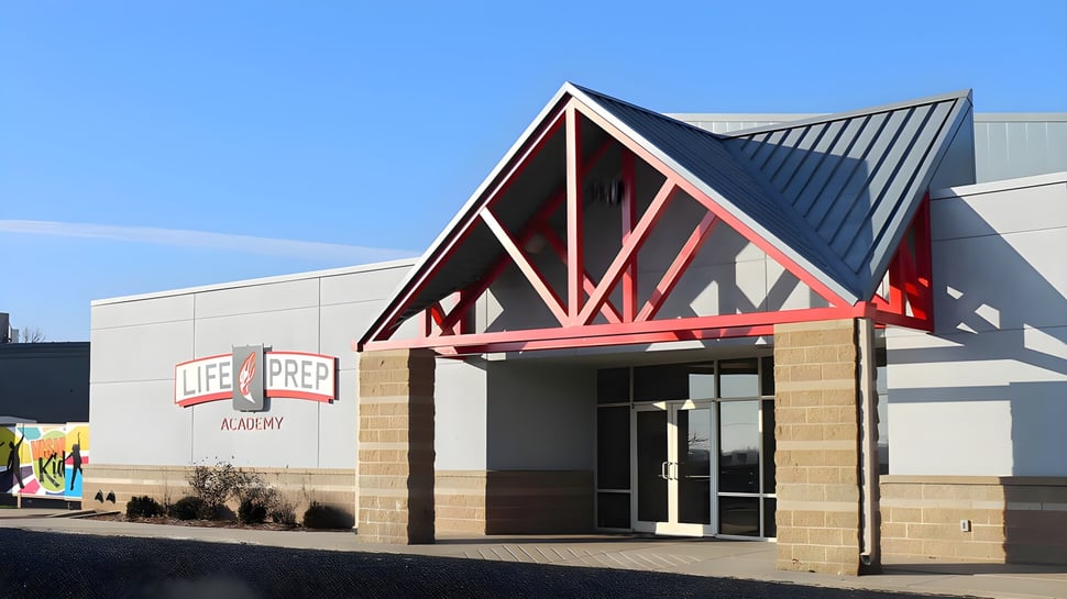 El moderno edificio con techo triangular de la Life Prep Academy se encuentra bajo un claro cielo azul.